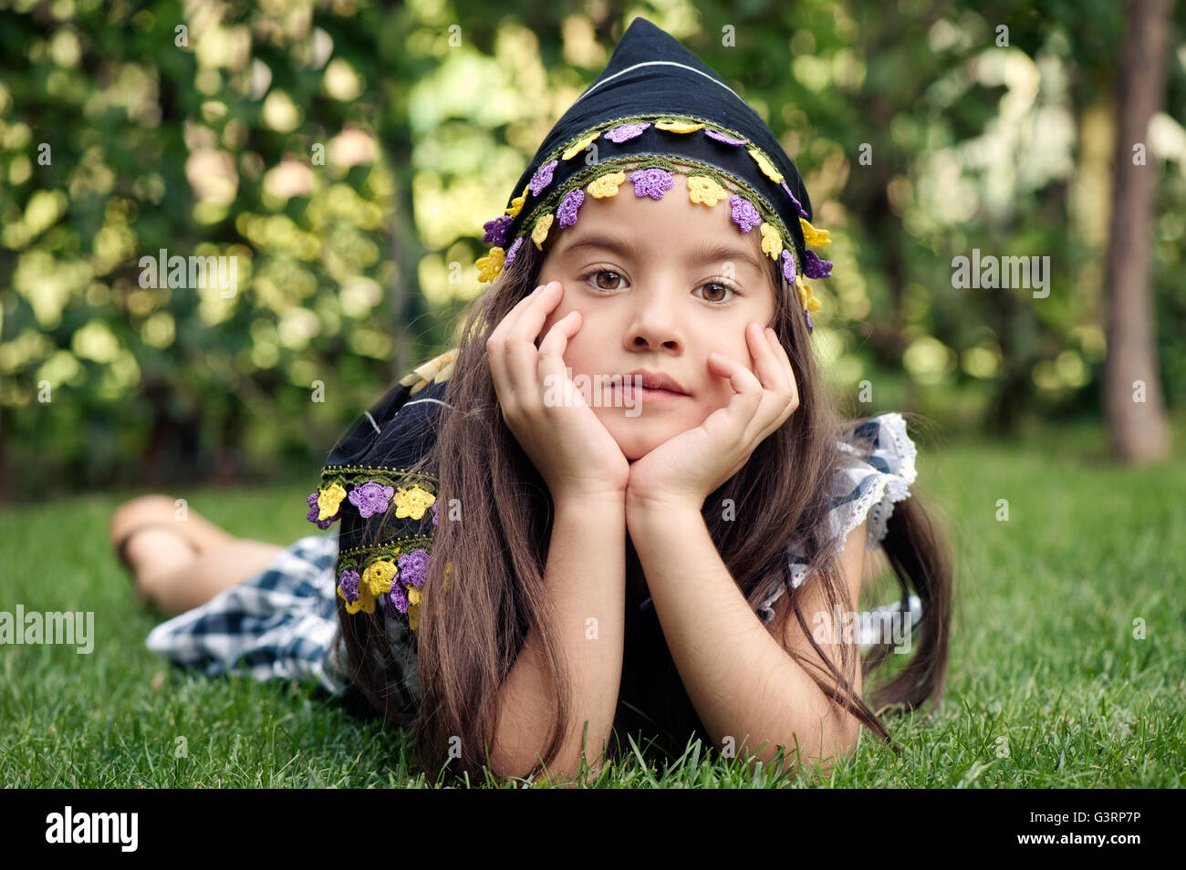Kleines Mädchen mit Kopftuch auf dem Rasen liegend Stockfoto