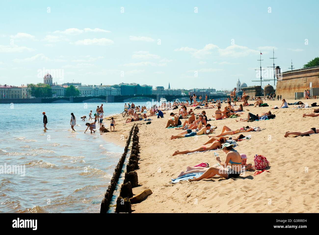 Sankt Petersburg in Russland. Sonnenbaden am Strand außerhalb der Mauern von Peter und Paul Fortress auf Zayachy Insel auf der Newa Stockfoto