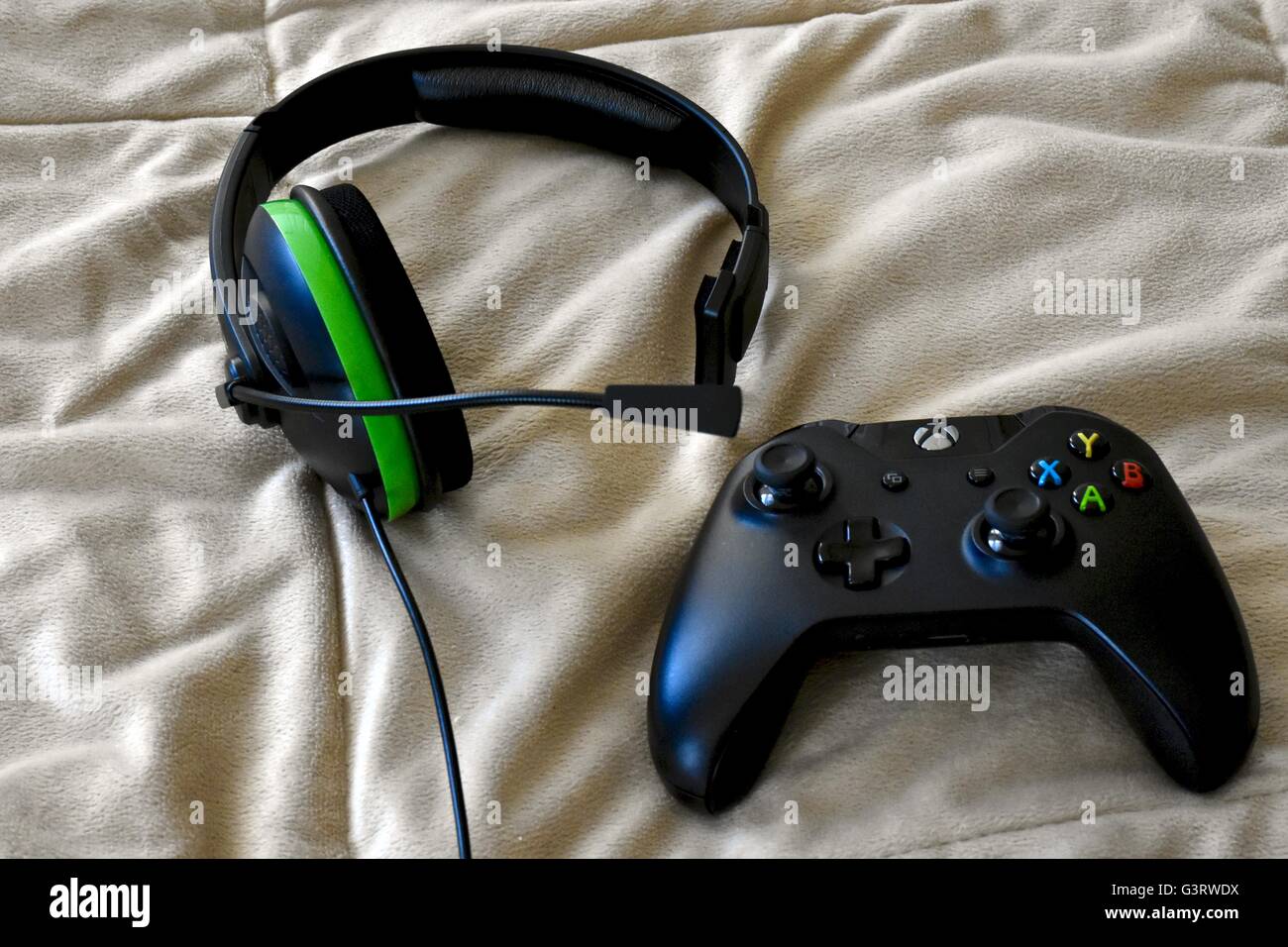 Eine Xbox One Controller und Kopfhörer auf einem Bett Stockfoto