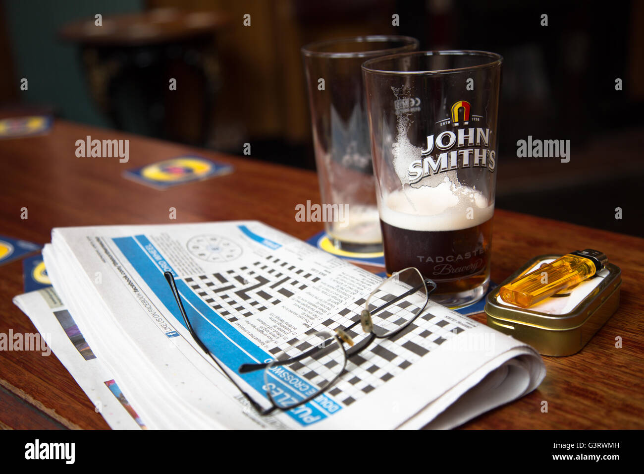 Ein Mittagessen Pause Blick auf die Tage lokale Kreuzworträtsel mit den Resten der ein Pint Bier/Ale in einem englischen Pub/Bar. Stockfoto