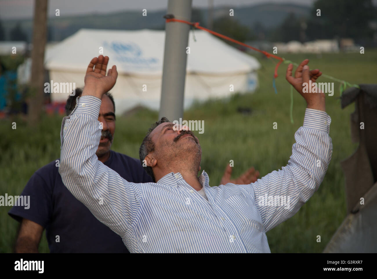 Ein kurdischer syrischen Mann tanzt und schaut in den Himmel im Flüchtlingslager Idomeni in Griechenland, in der Nähe von der mazedonischen Grenze. Stockfoto