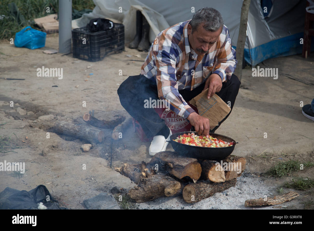 Eine syrische Kurden Mann Köche auf Protokolle und Feuer in der syrischen Flüchtlingslager Idomeni in Griechenland, in der Nähe von der mazedonischen Grenze. Stockfoto