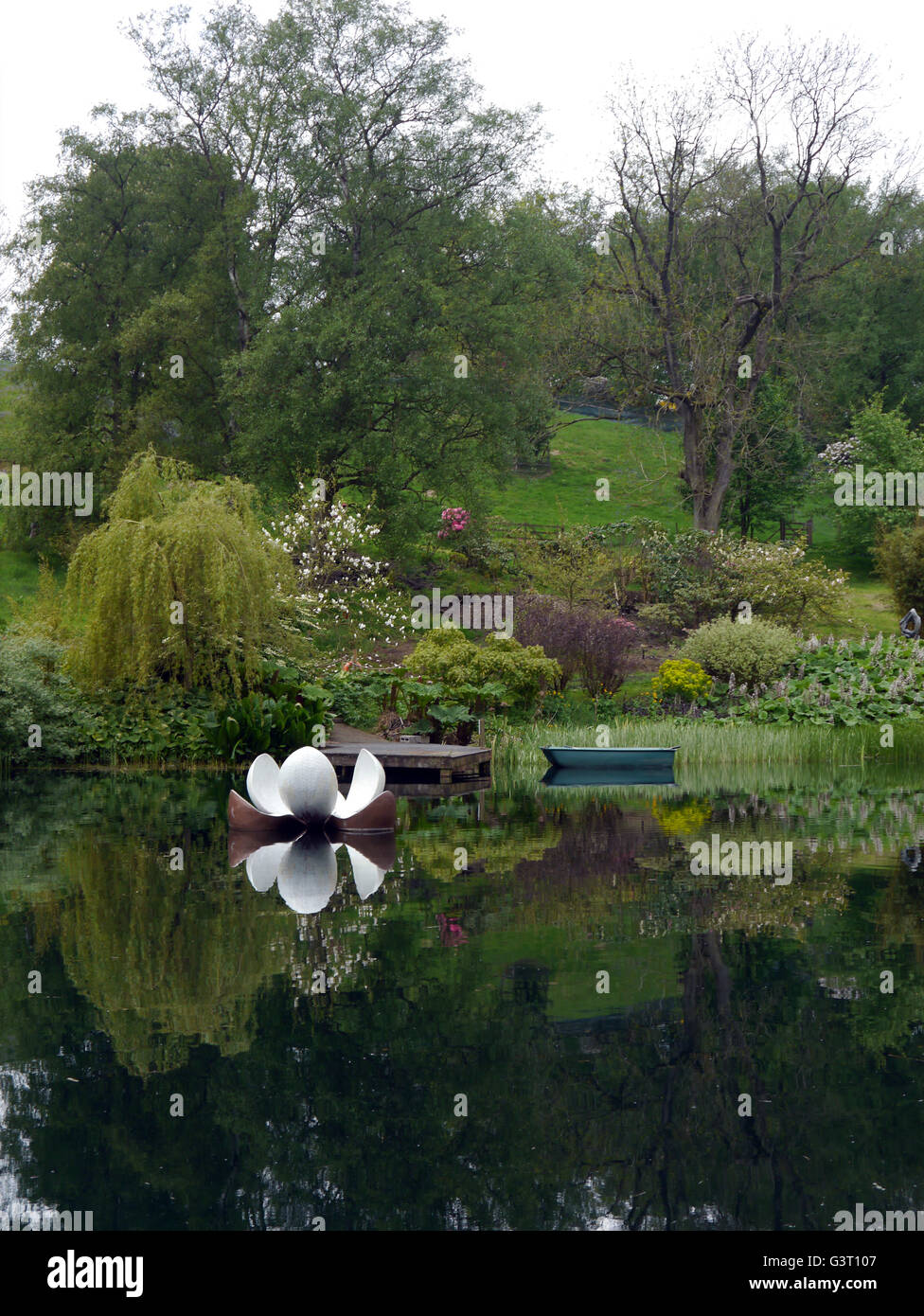 Ruderboot und Pier mit schwimmenden Skulptur auf See an der himalayan Garten & Skulpturen Park, North Yorkshire, England, UK. Stockfoto