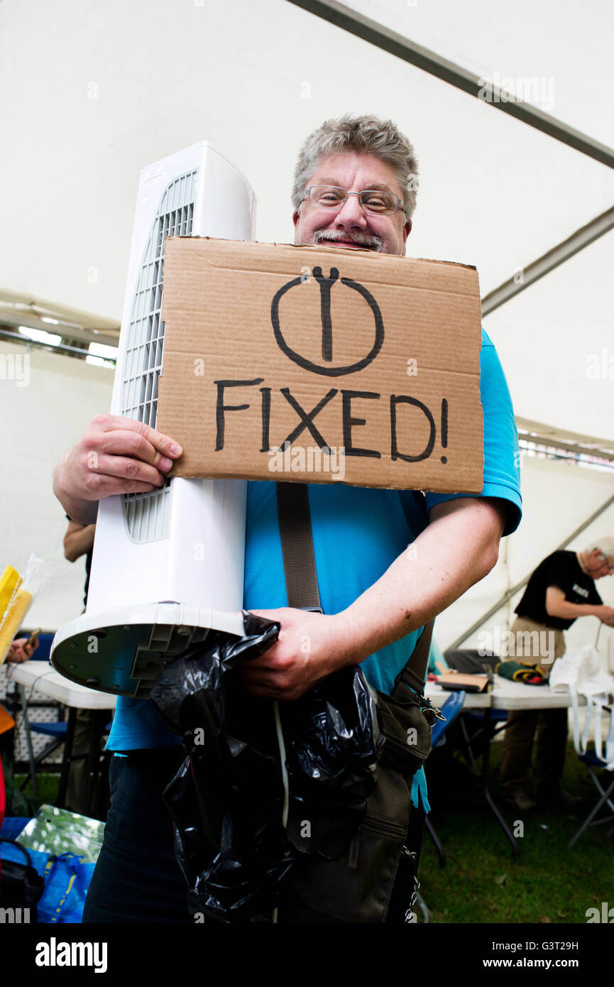 Starten Sie Projekt - Reparatur elektrischer Geräte neu. Ein Mann hält einen reparierten Ventilator und ein Schild mit der Aufschrift "fixiert". Stockfoto
