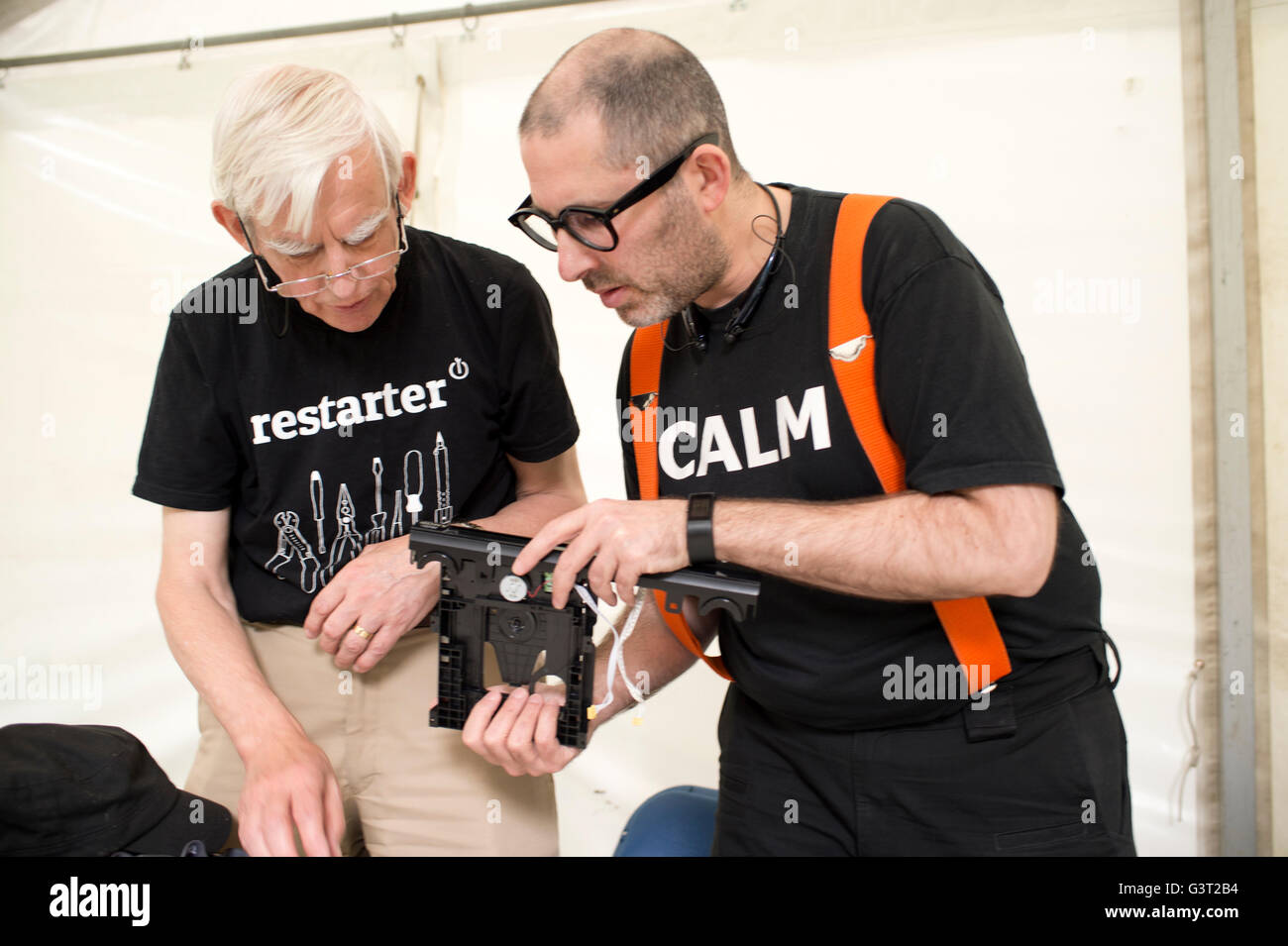 Starten Sie Projekt neu. Ein Mann trägt ein t Shirt sagt "Ruhe" repariert defekte dvd-Player, beobachtet von einem anderen Ingenieur Stockfoto