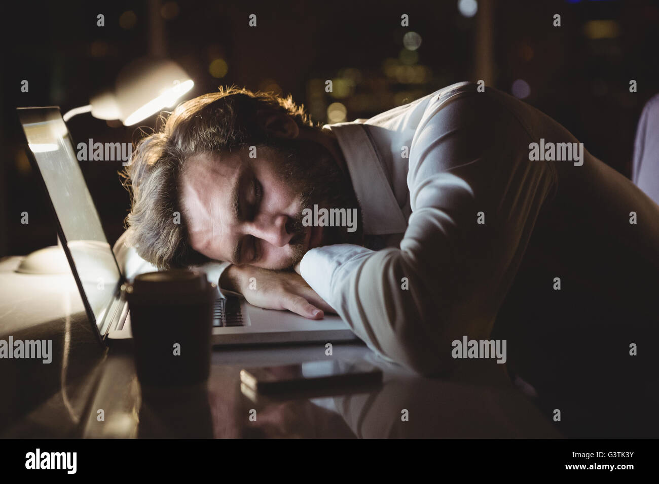 Geschäftsmann, schlafen auf seinem Laptop in der Nacht Stockfoto