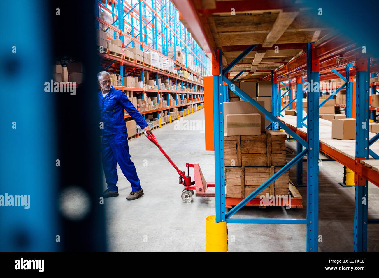 Mann-Arbeiter ziehen der Gabelhubwagen Stockfoto