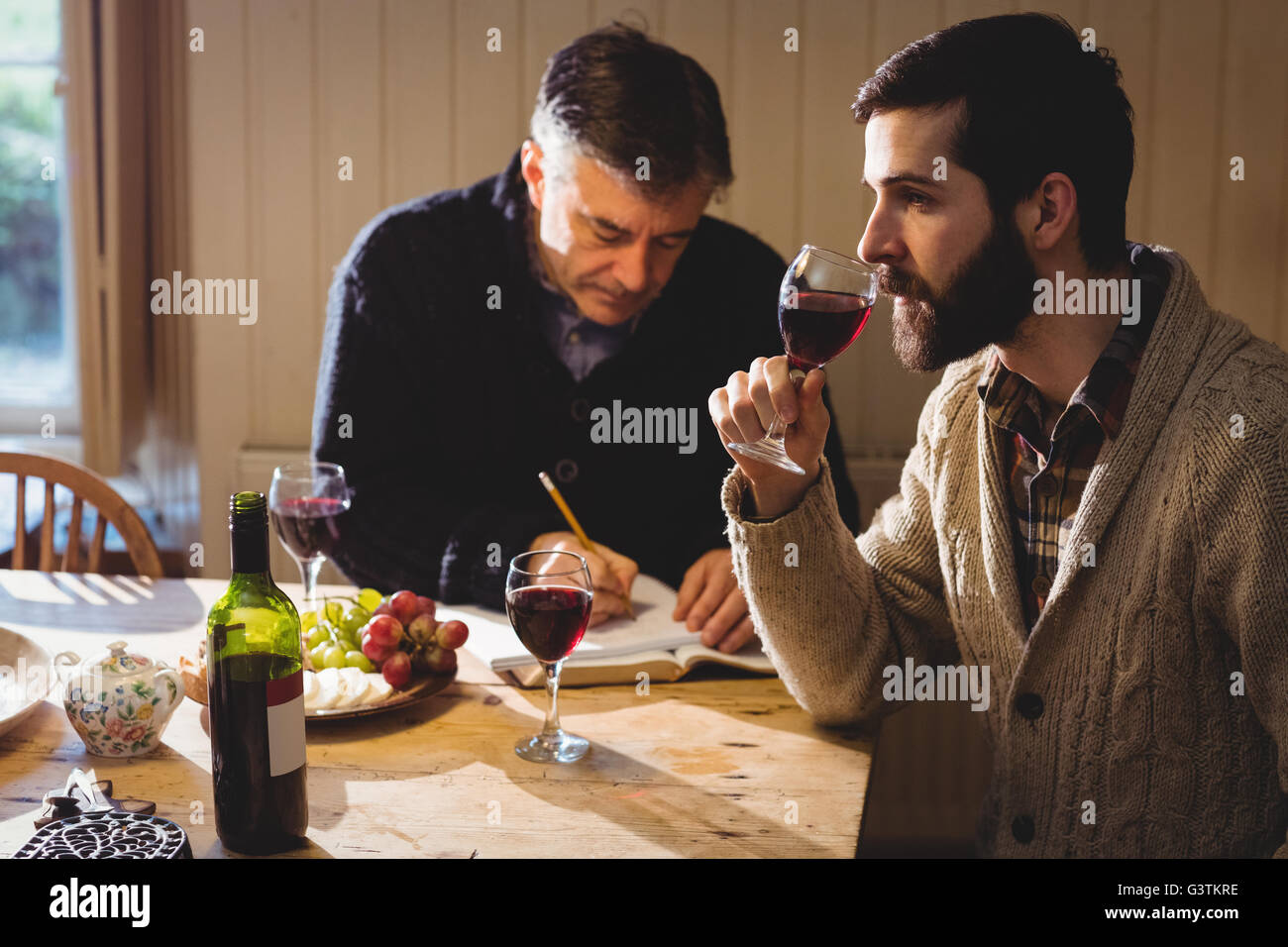 Hipster und reifer Mann Verkostung Rotwein und Notizen Stockfoto