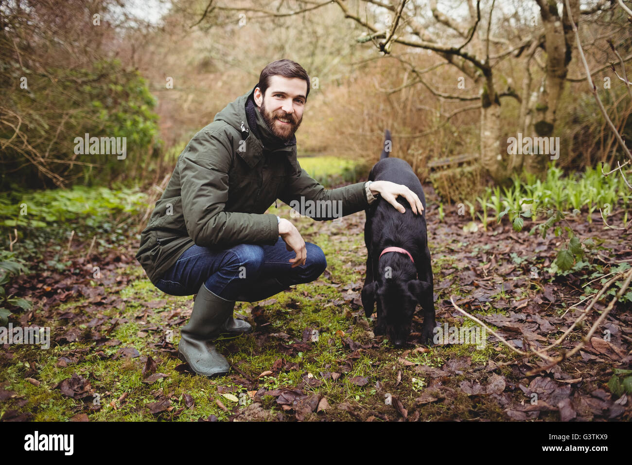 Hipster Mann lächelnd in die Kamera während streichelte seinen Hund Stockfoto