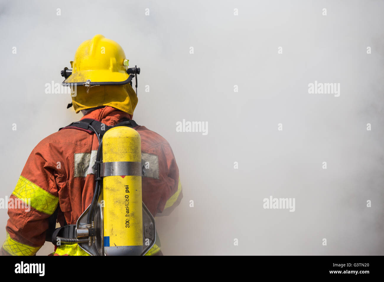 einzelne Feuerwehrmann ist Arbeits- und Surround mit Rauch Stockfoto