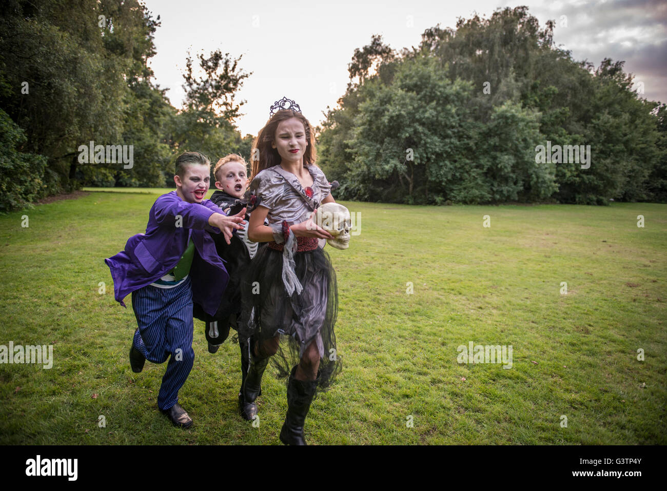 Kinder jagen eine Mädchen gekleidet wie ein Zombie Ballkönigin für Halloween-Nacht. Stockfoto