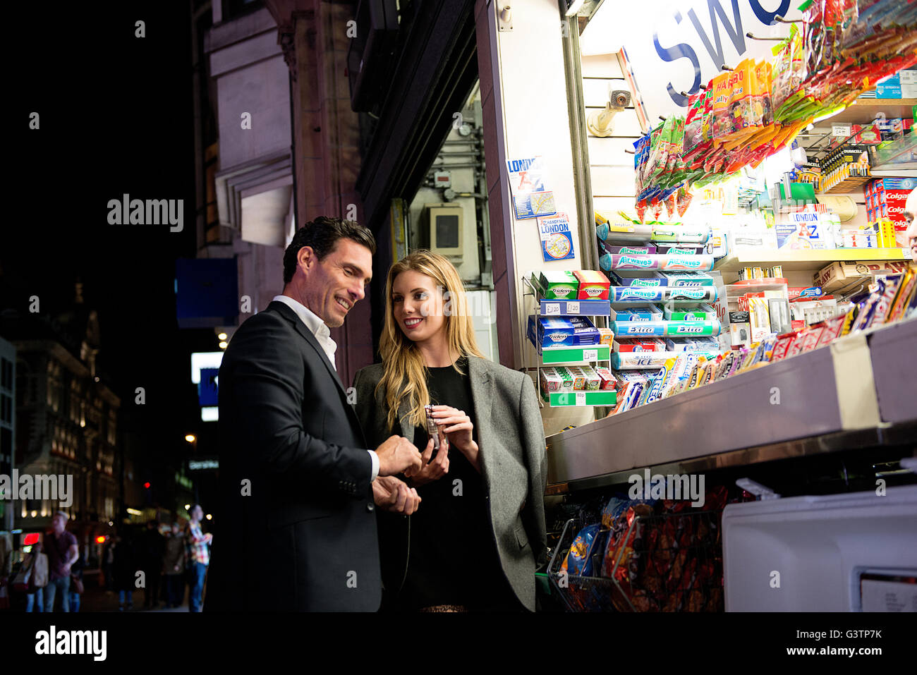 Ein elegant gekleidet paar Kauf von Süßwaren von einem Kiosk auf der Oxford Street in London. Stockfoto