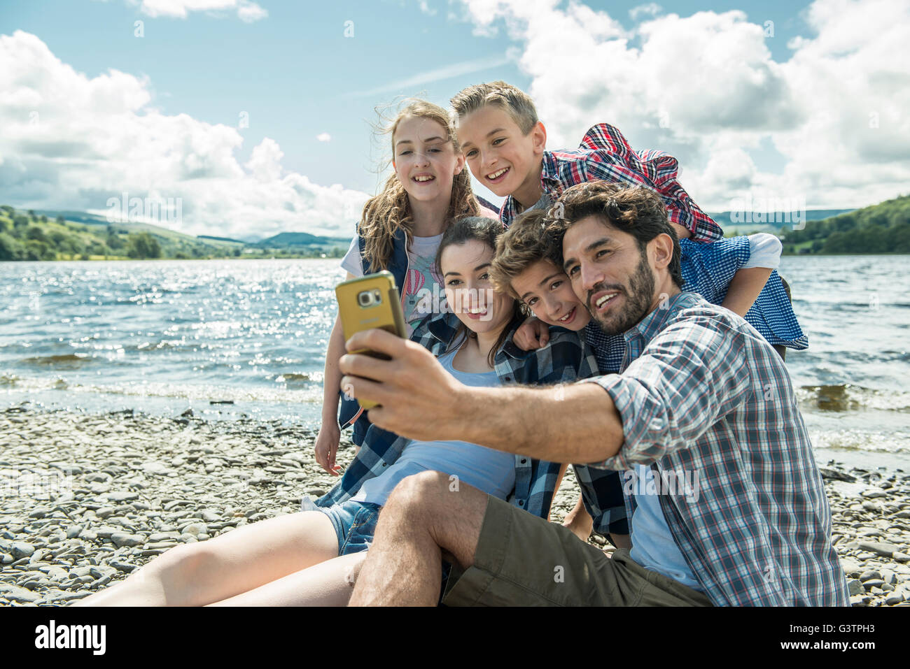 Eine fünfköpfige Familie unter einem Selfie am Ufer neben Bala Lake in Wales. Stockfoto