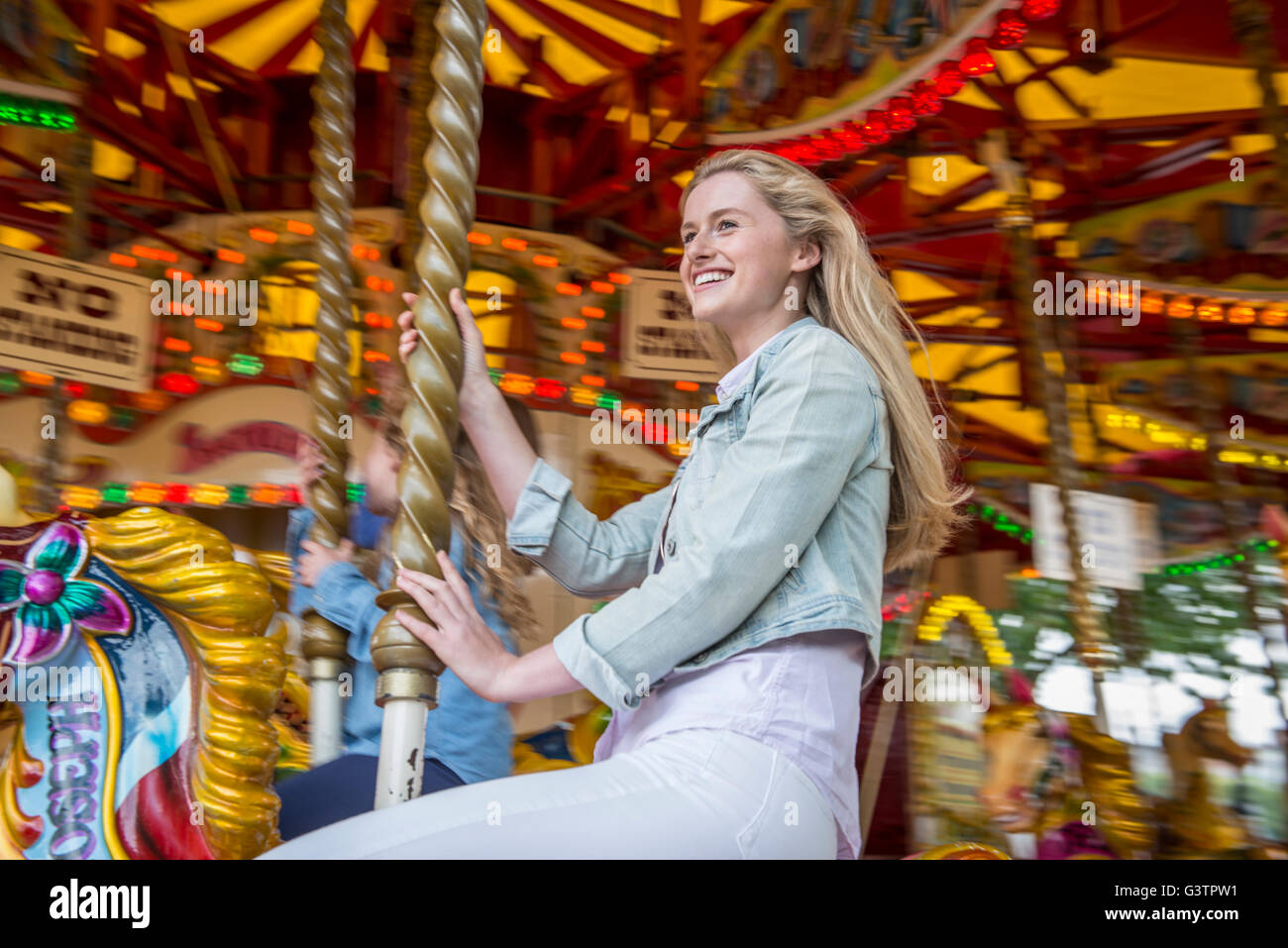 Ein attraktives blondes Mädchen reiten ein Karussell auf der South Bank in London. Stockfoto