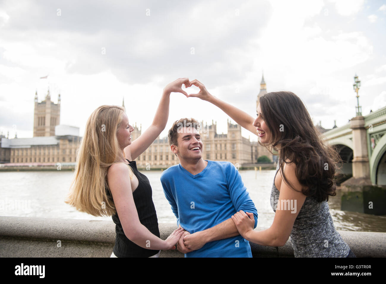 Drei Freunde machen eine Herzform mit ihren Händen mit den Houses of Parliament im Hintergrund. Stockfoto