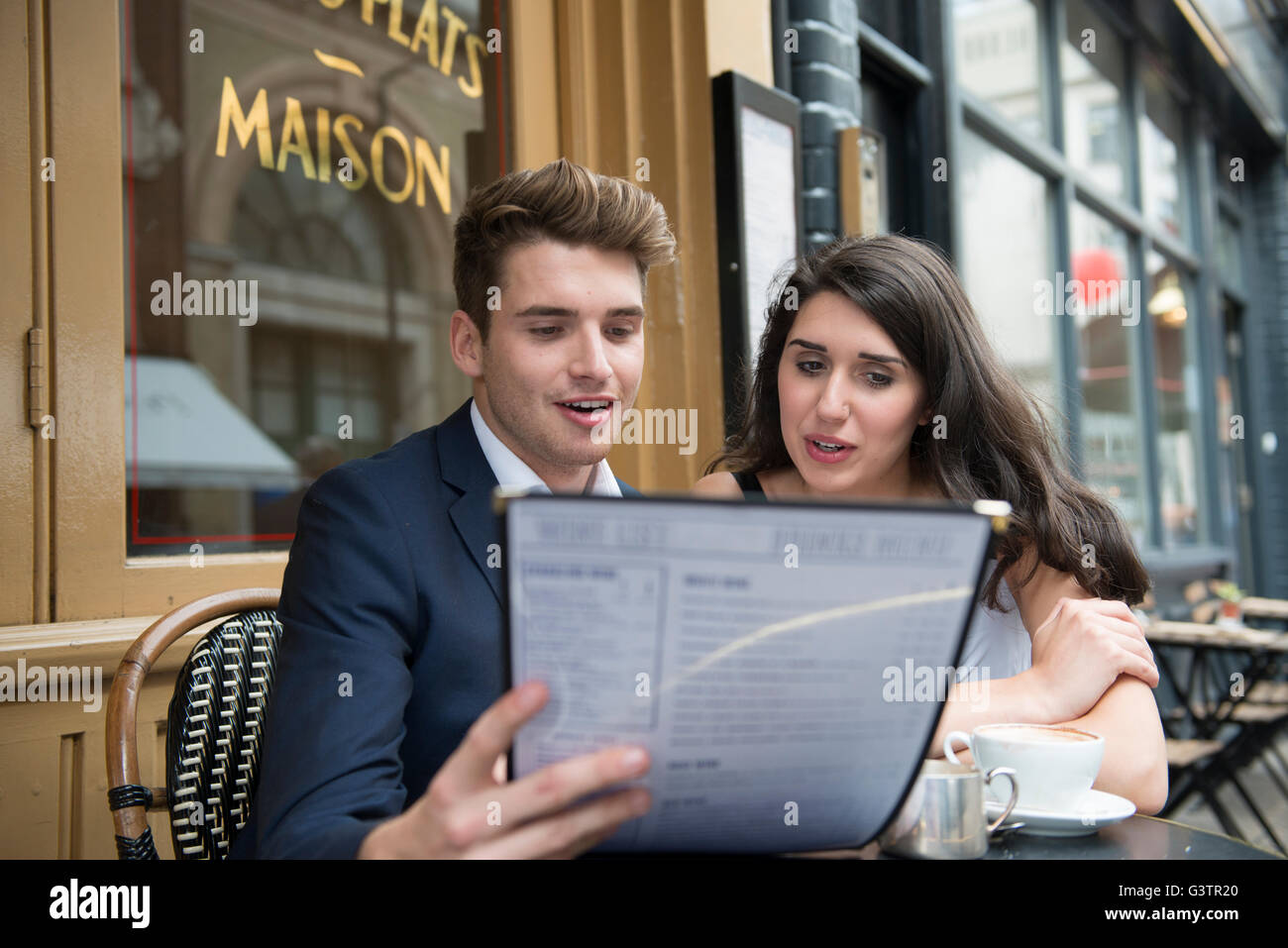 Ein junges Paar, Blick auf eine Speisekarte vor einem Café in Covent Garden in London. Stockfoto
