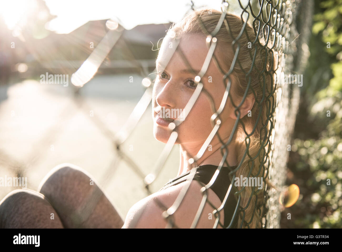 Eine junge Frau, die genießen der Abendsonne setzte sich auf einen Tennisplatz. Stockfoto