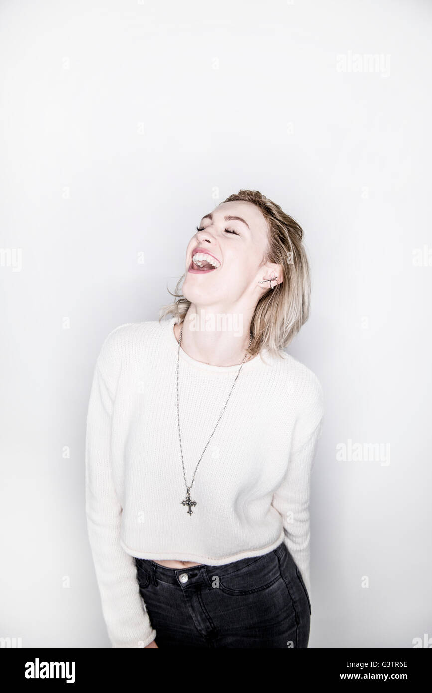Eine attraktive junge Frau posiert in einem Studio lachen. Stockfoto