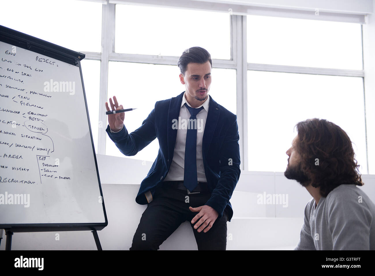 Zwei Arbeitskollegen diskutieren Strategie vor einem Flip-Chart in einem Bürogebäude. Stockfoto