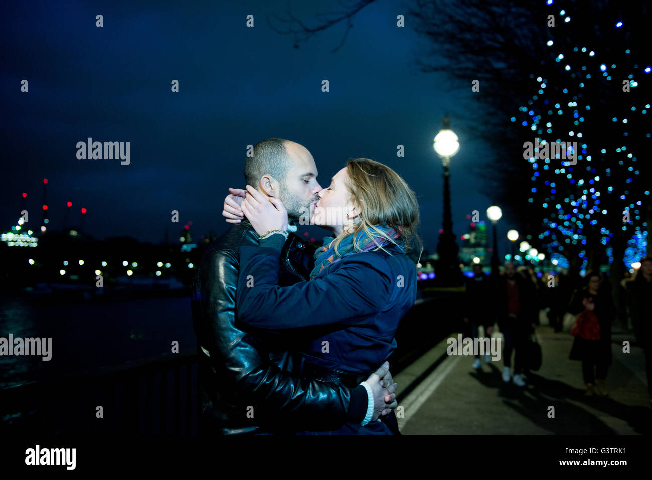 Ein paar küssen entlang der South Bank in London in der Nacht. Stockfoto