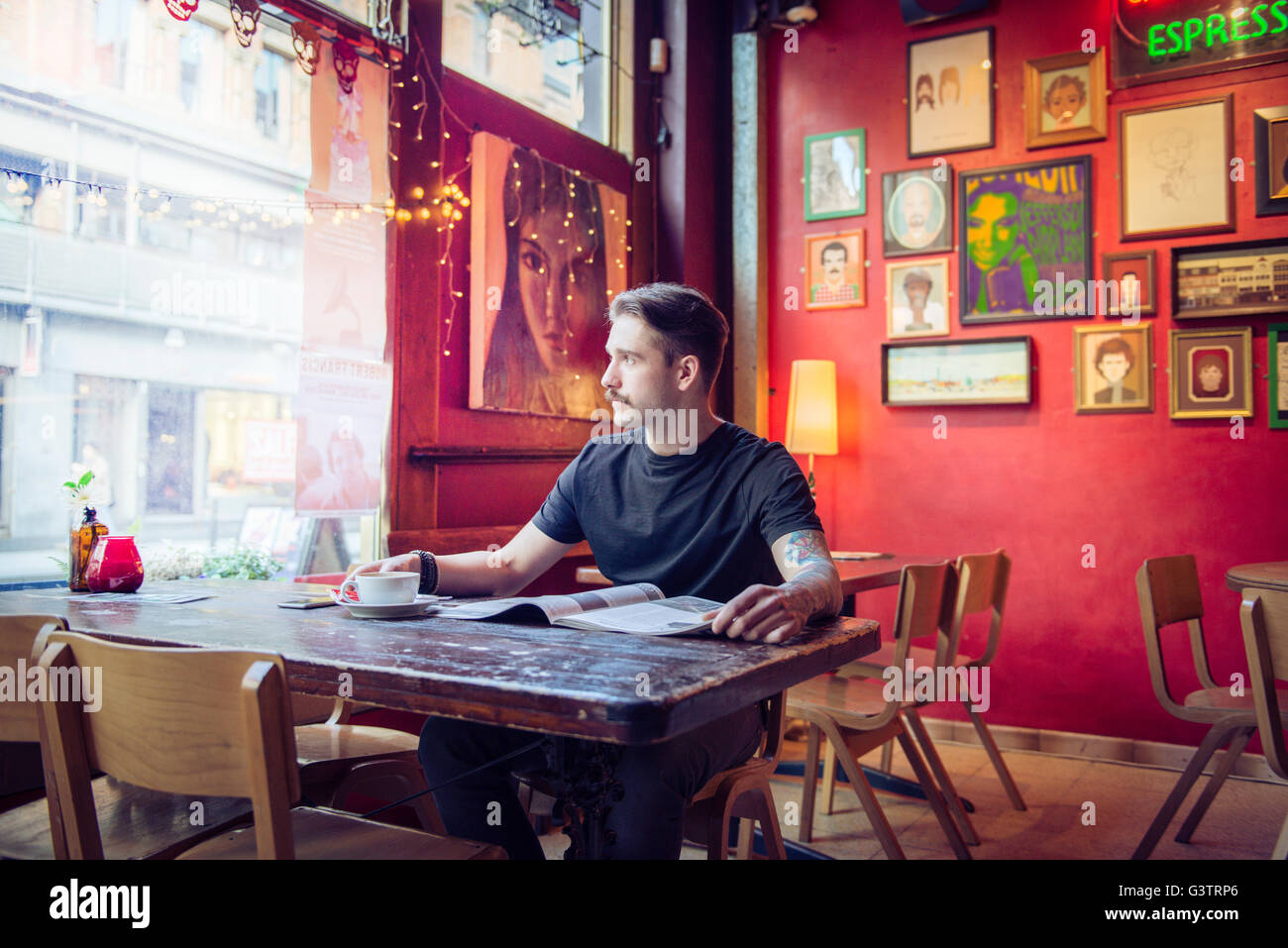 Ein junger Mann sitzt an einem Tisch in einem Café in Manchester. Stockfoto