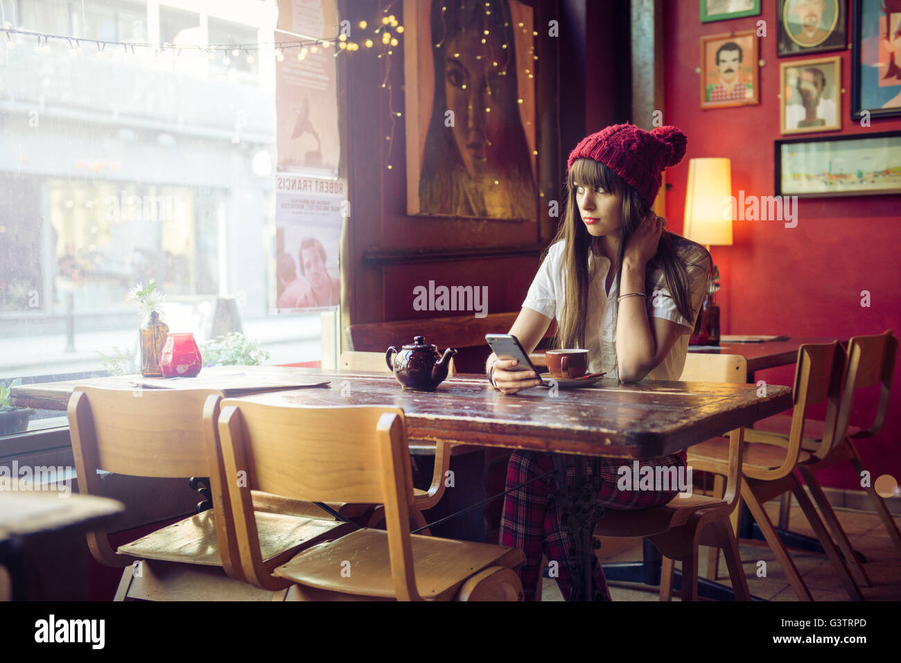 Eine junge Frau sitzt an einem Tisch in einem Café in Manchester. Stockfoto