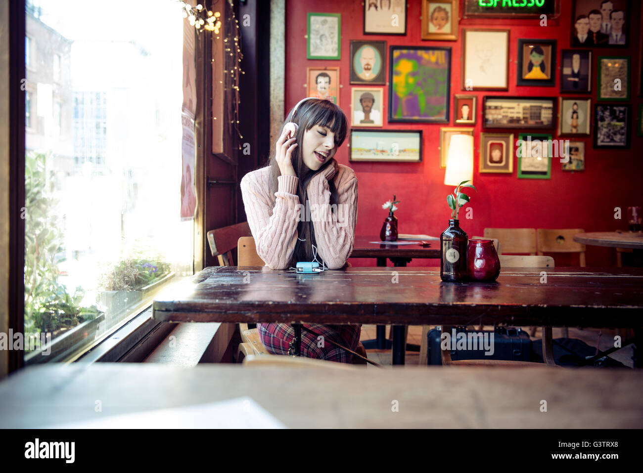 Eine junge Frau sitzt an einem Tisch in einem Café in Manchester. Stockfoto