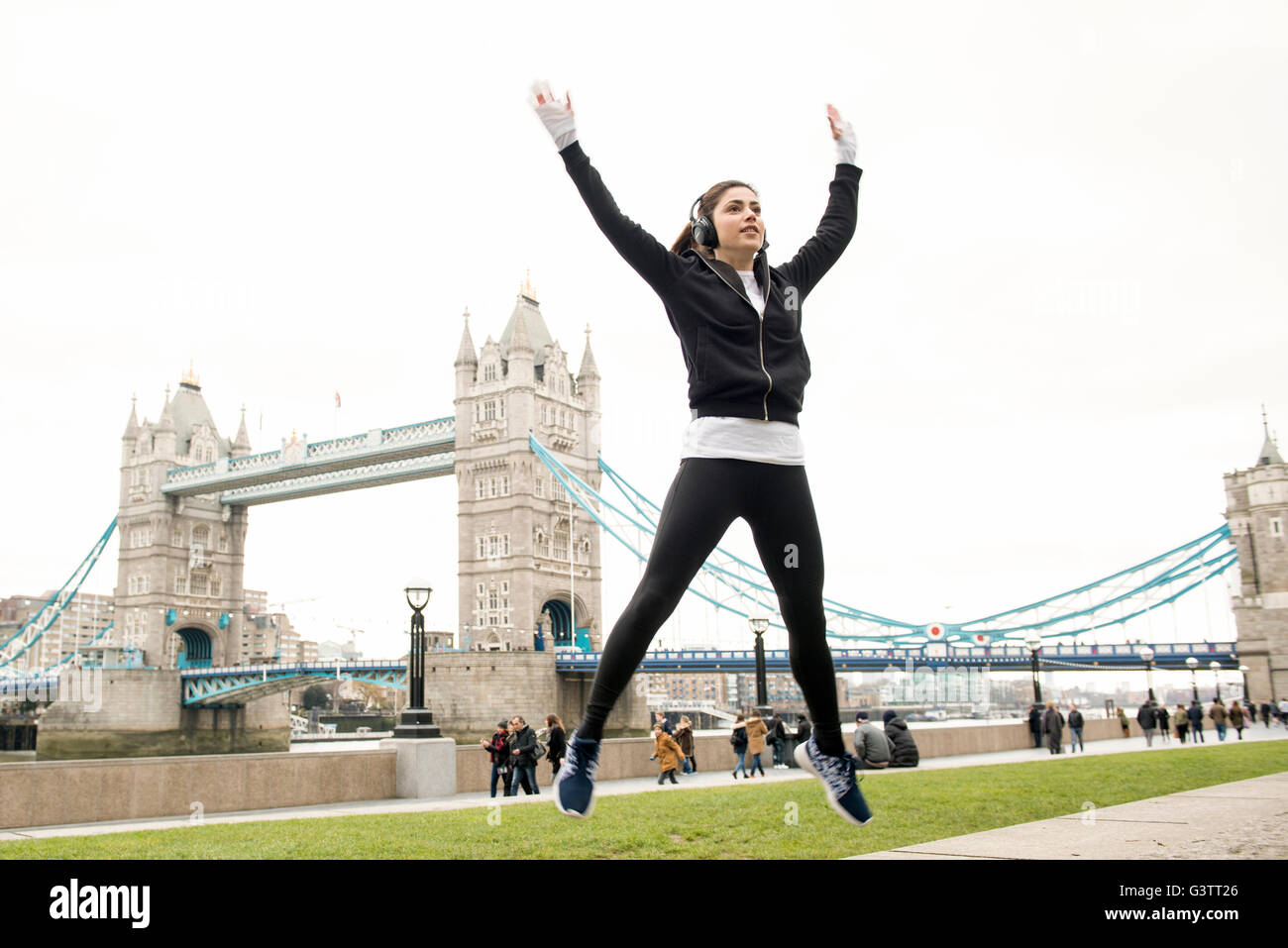 Eine junge Frau Lockerungsübungen bis zum Joggen in der Nähe von Tower Bridge in London. Stockfoto