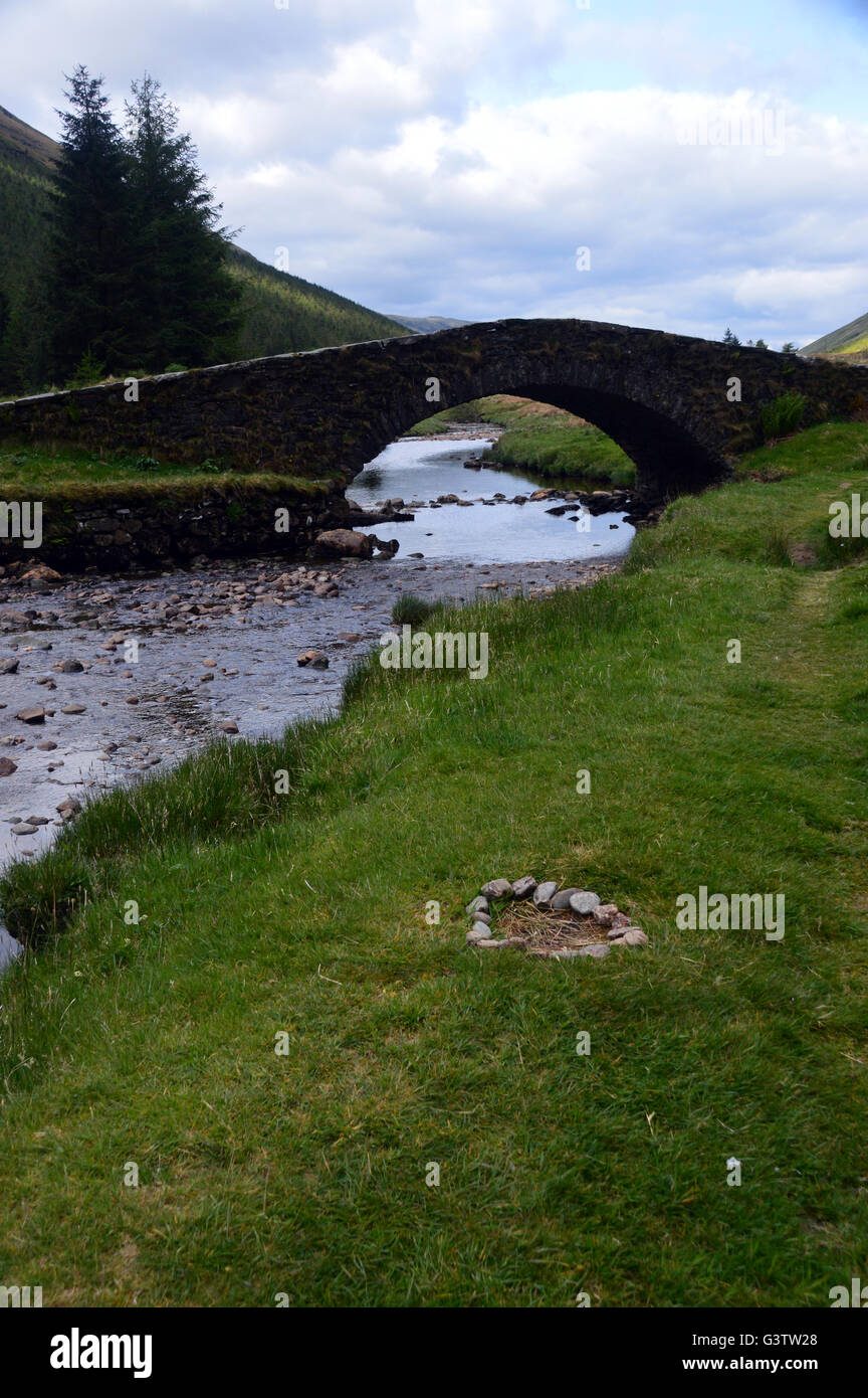 Ring aus Steinen von einem Lagerfeuer durch die alte Single gewölbte Brücke über den Fluss Kinglas Butterbridge Highlands von Schottland, Vereinigtes Königreich. Stockfoto