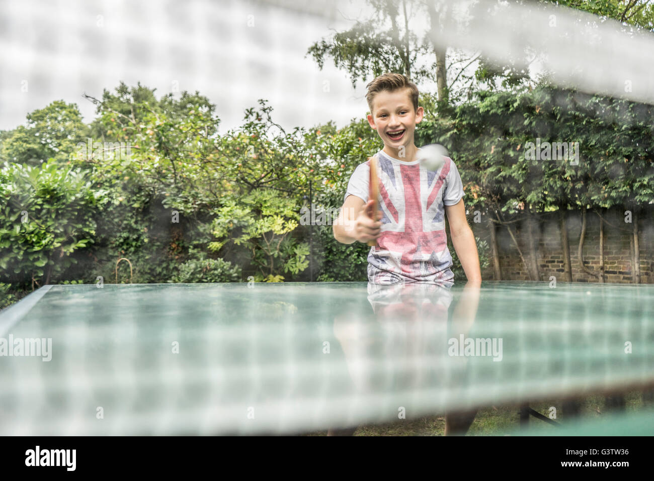 Ein zwölf Jahre alter Junge Tischtennis außerhalb. Stockfoto