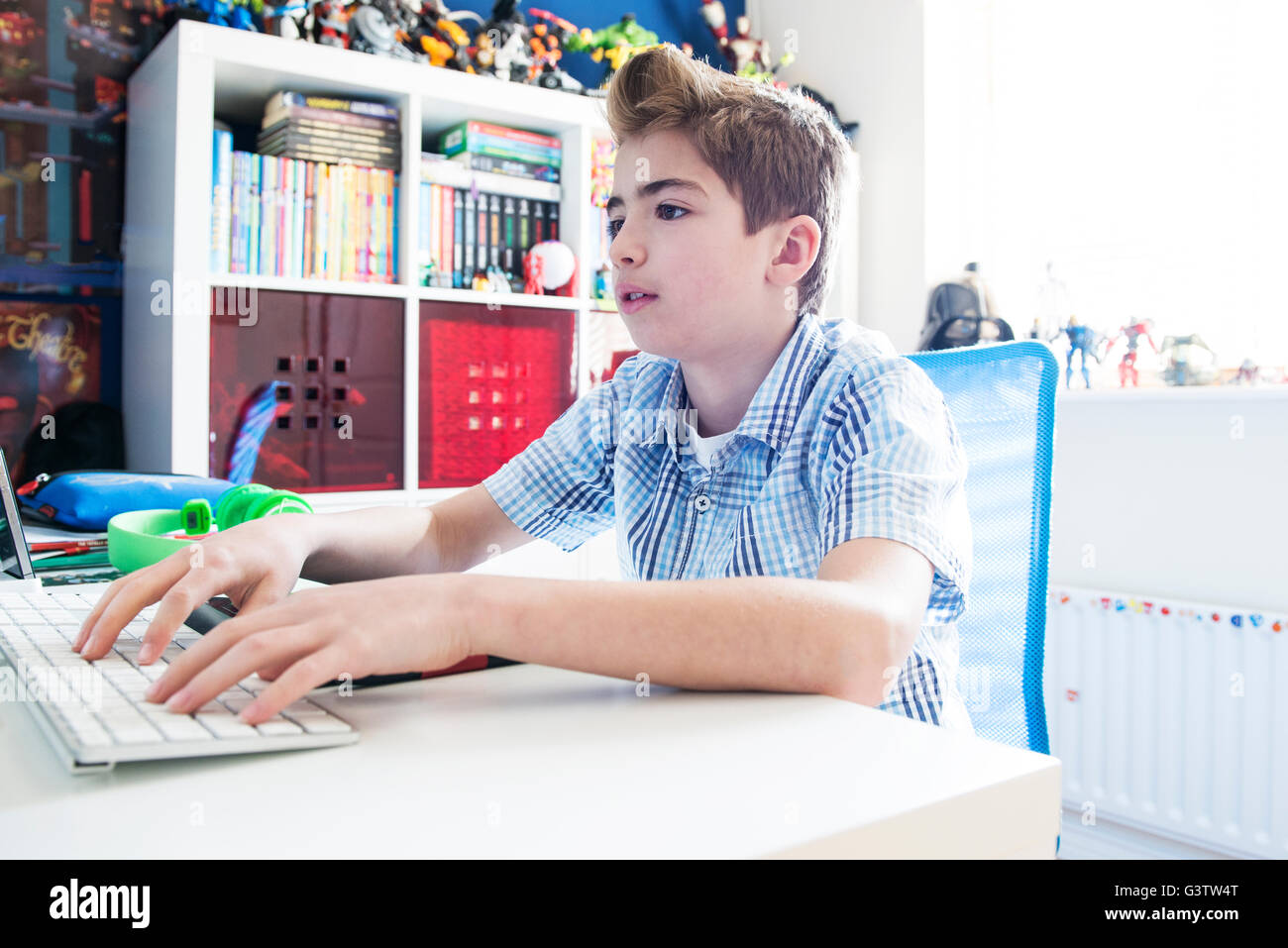 Ein zehn Jahre alter Junge sitzt an einem Computer in seinem Schlafzimmer. Stockfoto