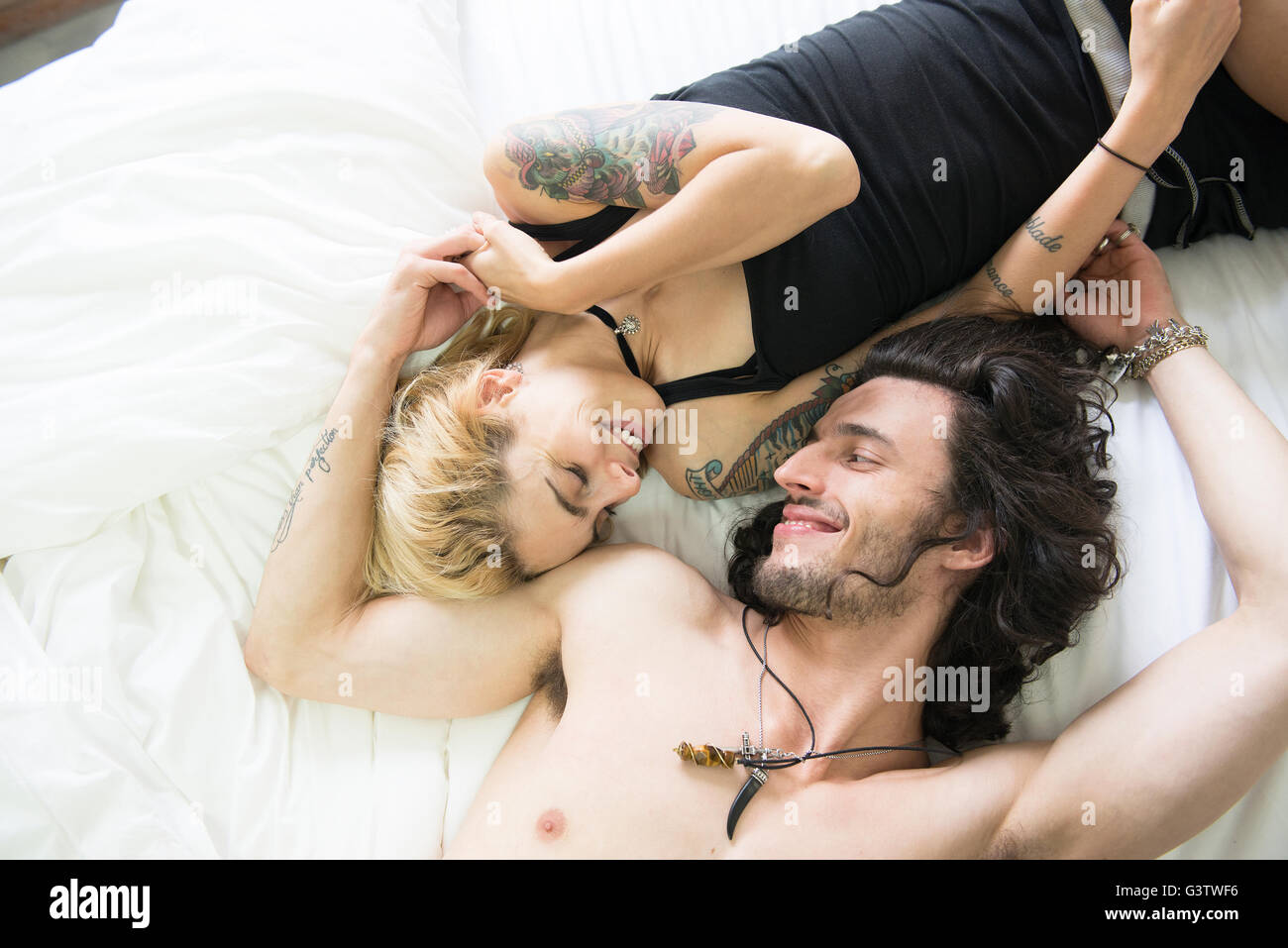 Eine coole junge Tätowierte Paar gemeinsam auf einem Bett liegend. Stockfoto