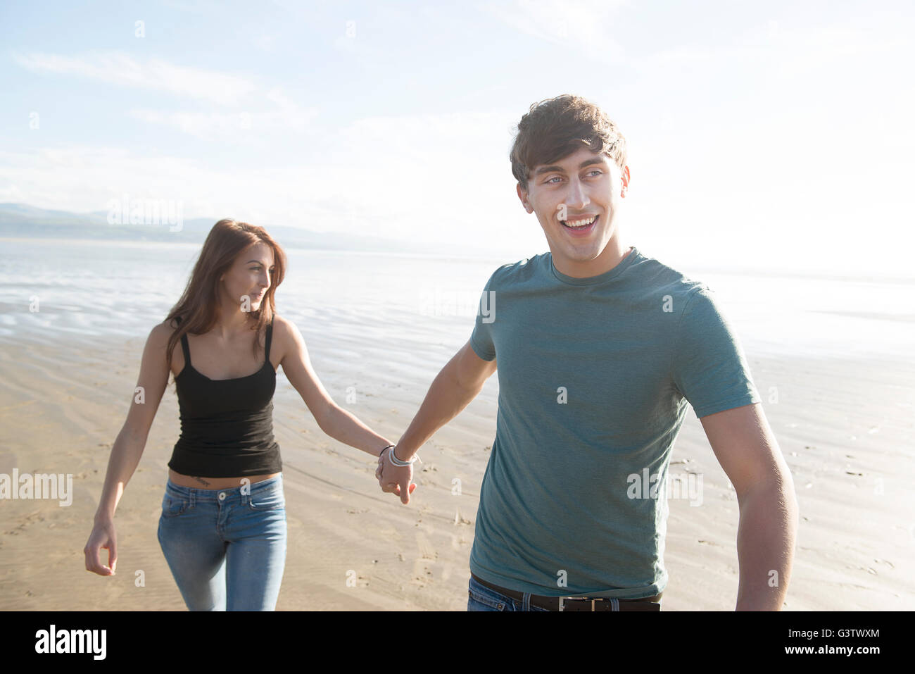 Ein junges Paar halten die Hände am Strand von Porthmadog. Stockfoto