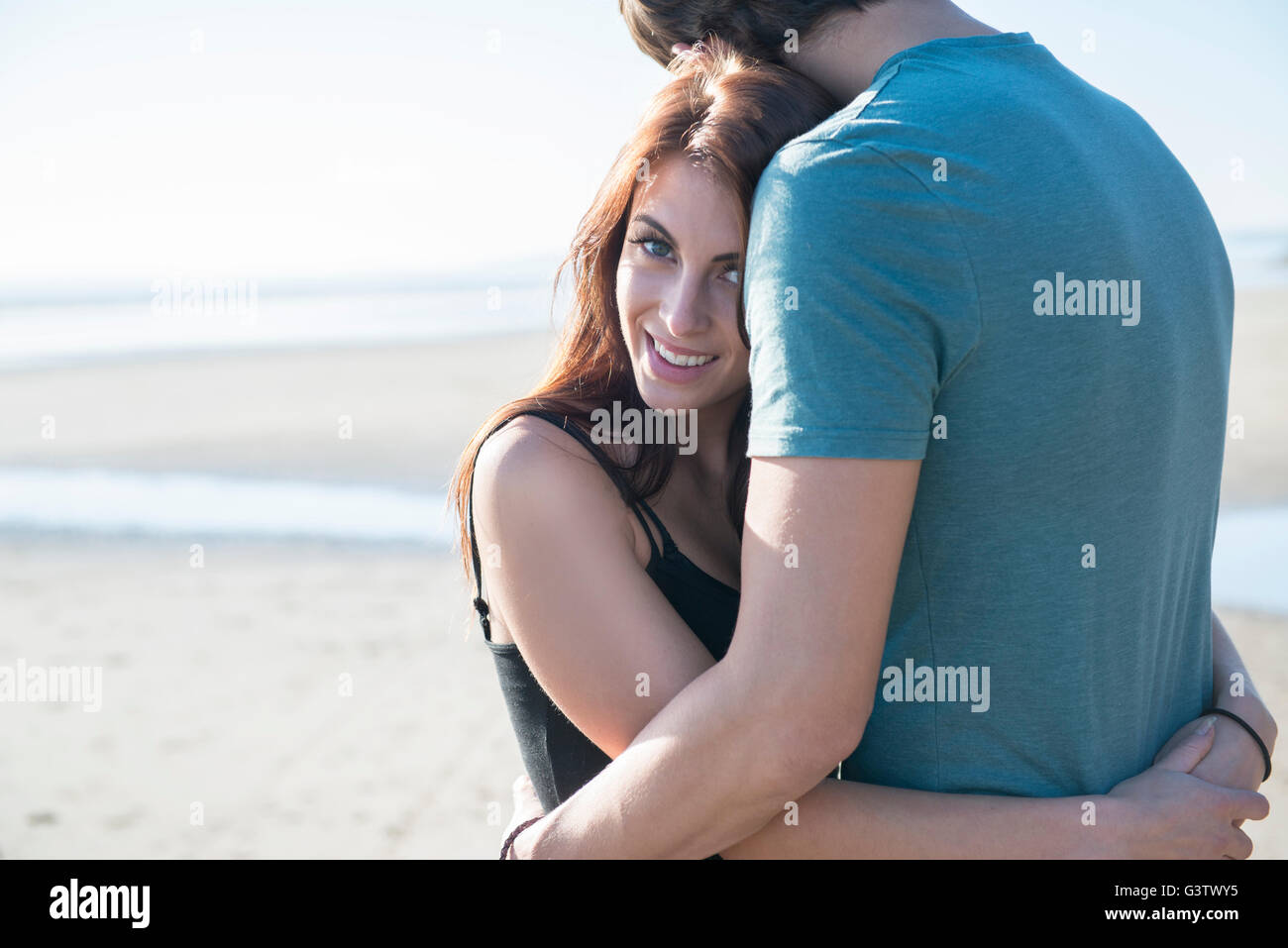 Ein junges Paar am Strand von Porthmadog umarmen. Stockfoto