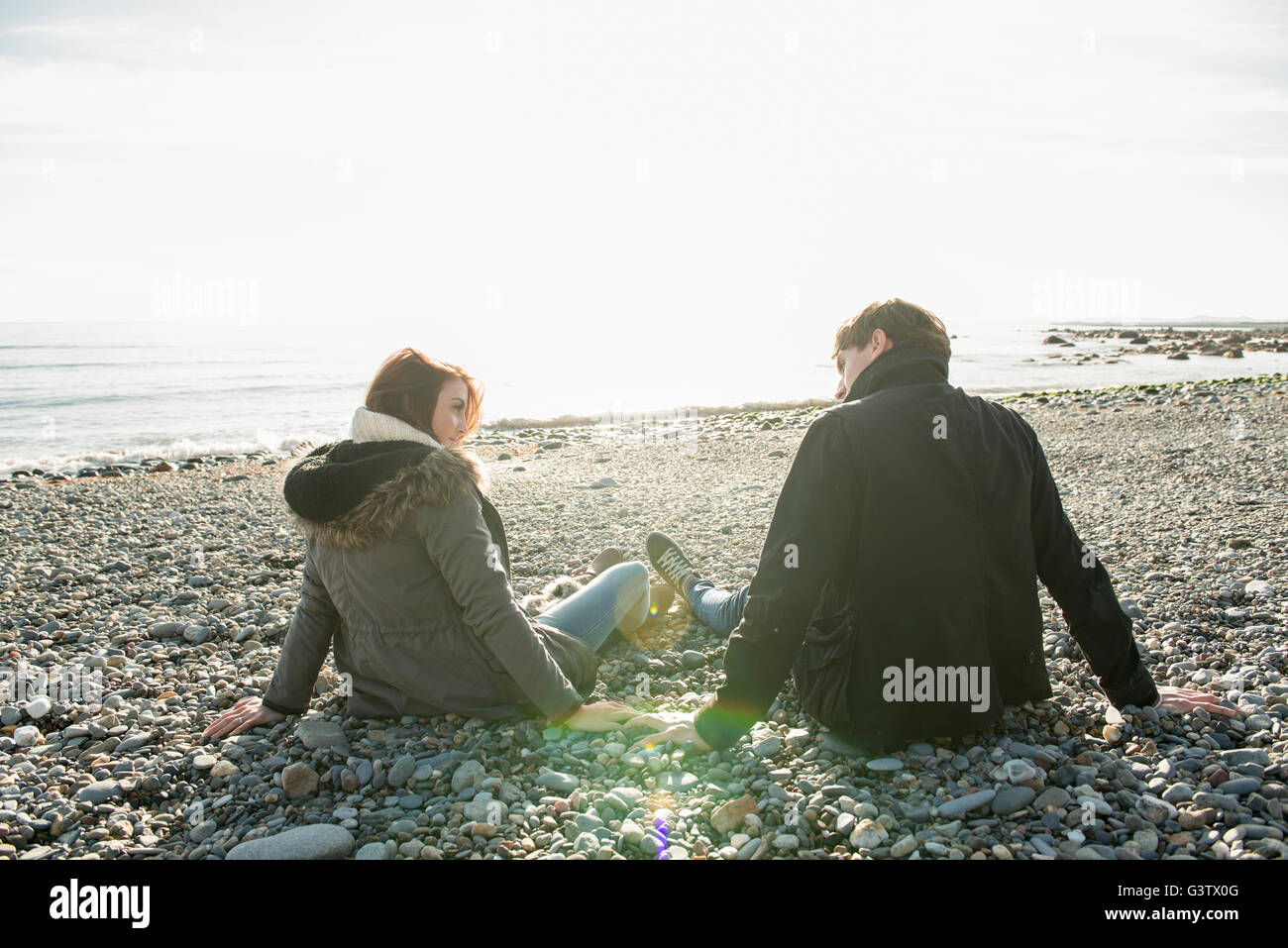 Ein junges Paar, genießen die Sonne am Strand von Porthmadog. Stockfoto