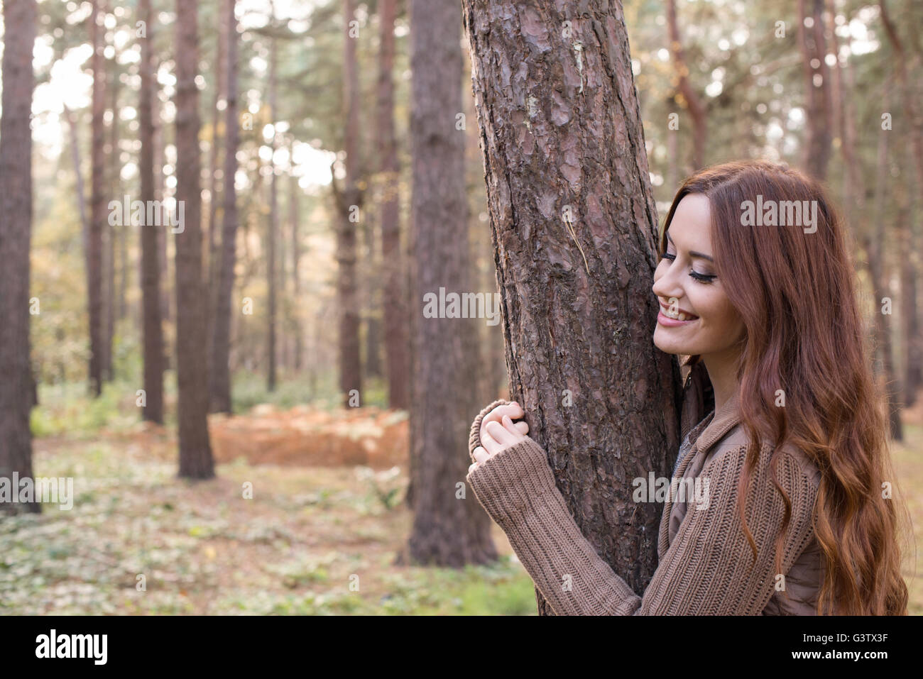 Eine junge Frau, die Zwiesprache mit der Natur in einem Wald im Herbst. Stockfoto