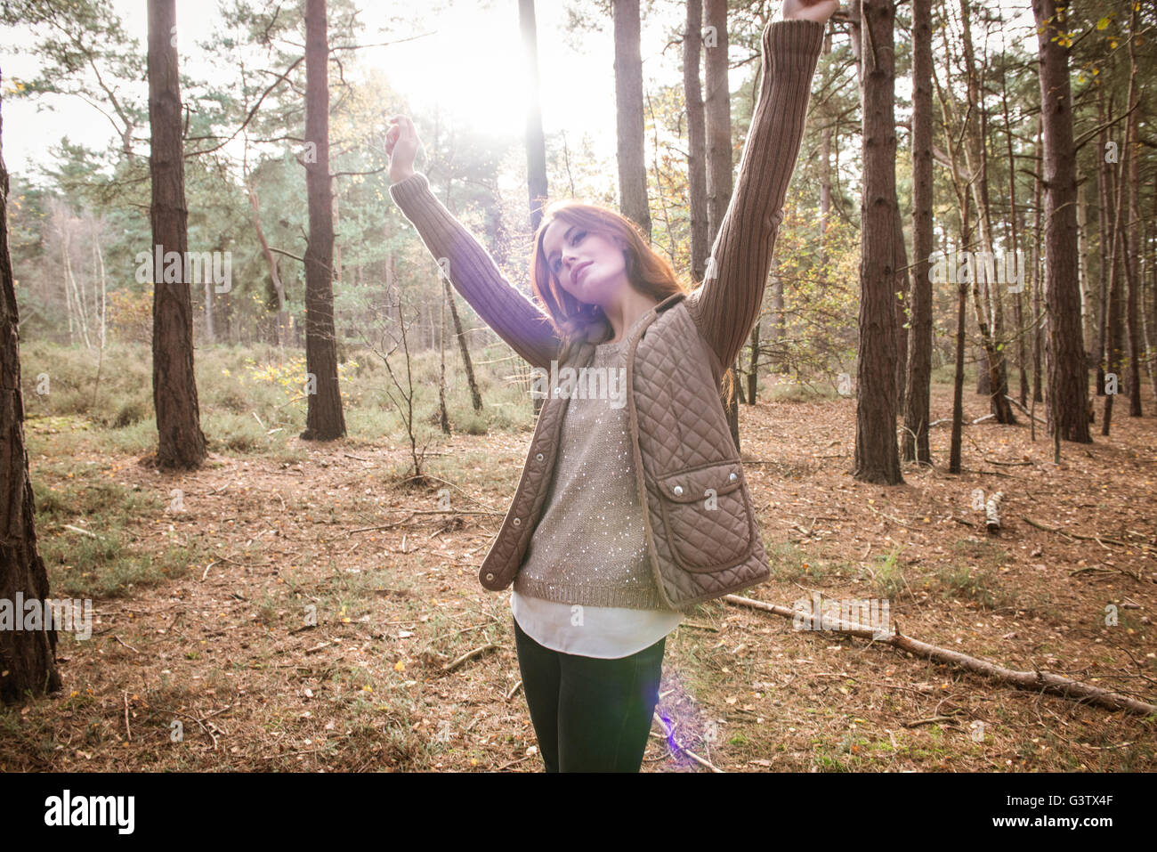 Eine junge Frau, die Zwiesprache mit der Natur in einem Wald im Herbst. Stockfoto
