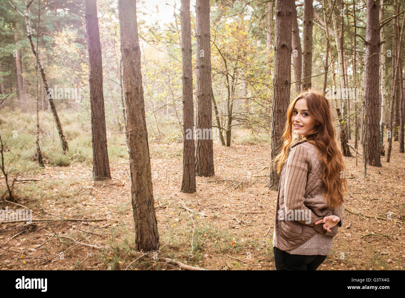 Eine junge Frau, die Zwiesprache mit der Natur in einem Wald im Herbst. Stockfoto