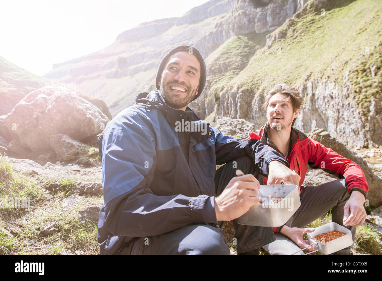 Zwei Bergsteiger sitzen Essen in unwegsamem Gelände. Stockfoto