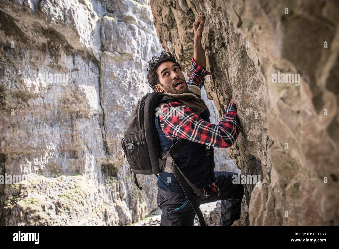 Ein Bergsteiger, einen Felsvorsprung in unwegsamem Gelände zu durchqueren. Stockfoto