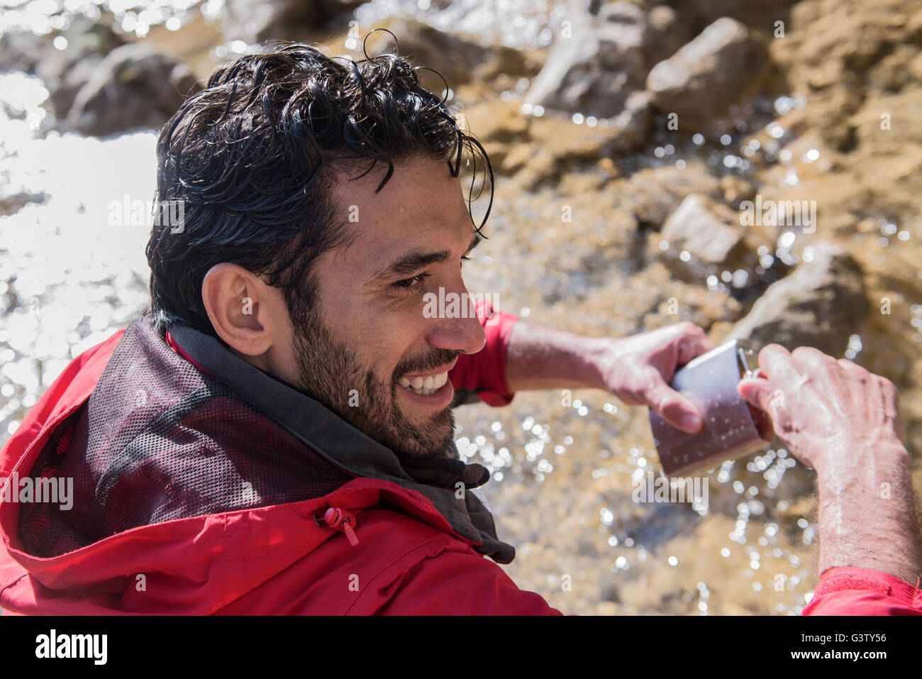 Ein Bergsteiger, füllt seine Flasche Wasser aus einem Gebirgsbach. Stockfoto