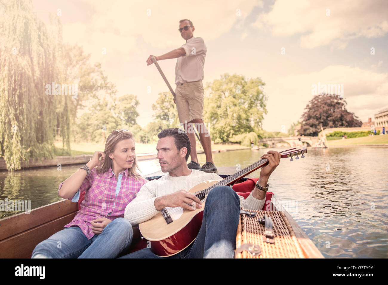 Ein paar mit einer Gitarre, sitzend in einem Kahn auf dem Fluss Cam in Cambridge. Stockfoto