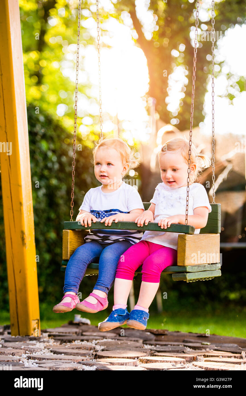 Zwei schöne kleine Mädchen schwingen im Park. Stockfoto