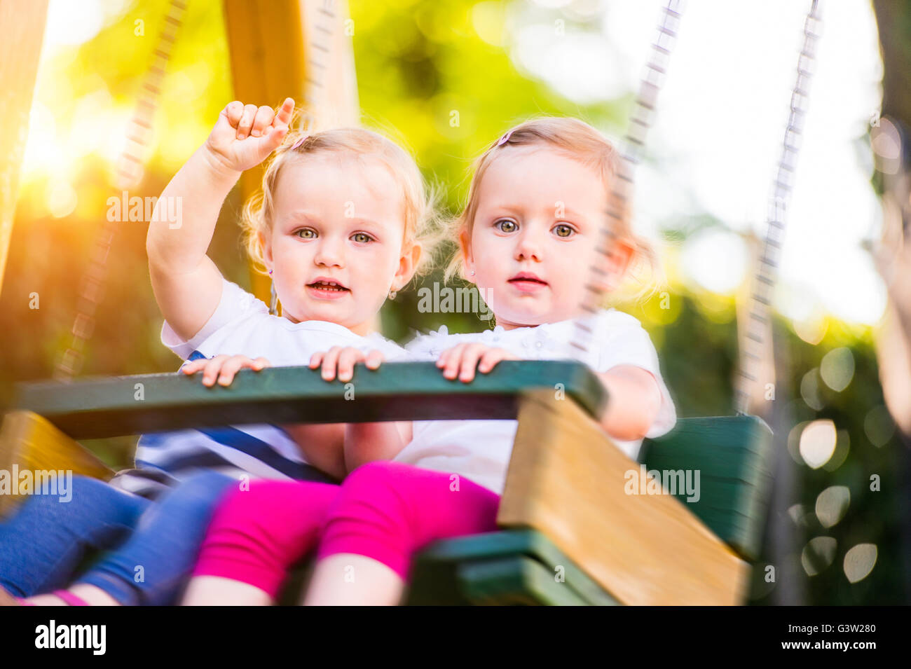 Zwei schöne kleine Mädchen schwingen im Park. Stockfoto