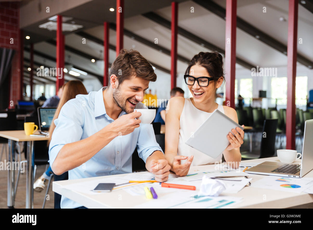 Fröhliche junge Geschäftsleute lachen zusammen und arbeiten im Büro Stockfoto