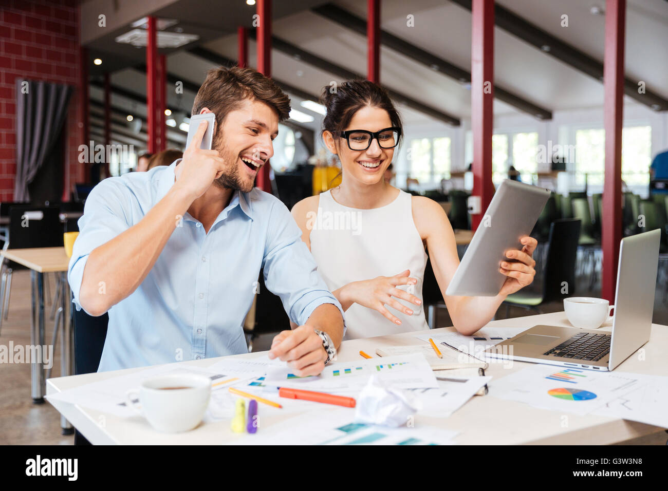 Gerne schöne junge Geschäftsleute sprechen auf Handy und mit Tablette zusammen im Büro Stockfoto