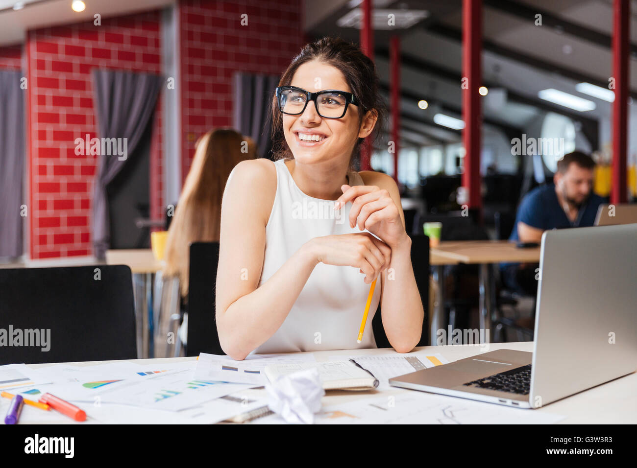 Porträt des Lächelns hübsche junge Geschäftsfrau in Gläsern sitzen am Arbeitsplatz Stockfoto