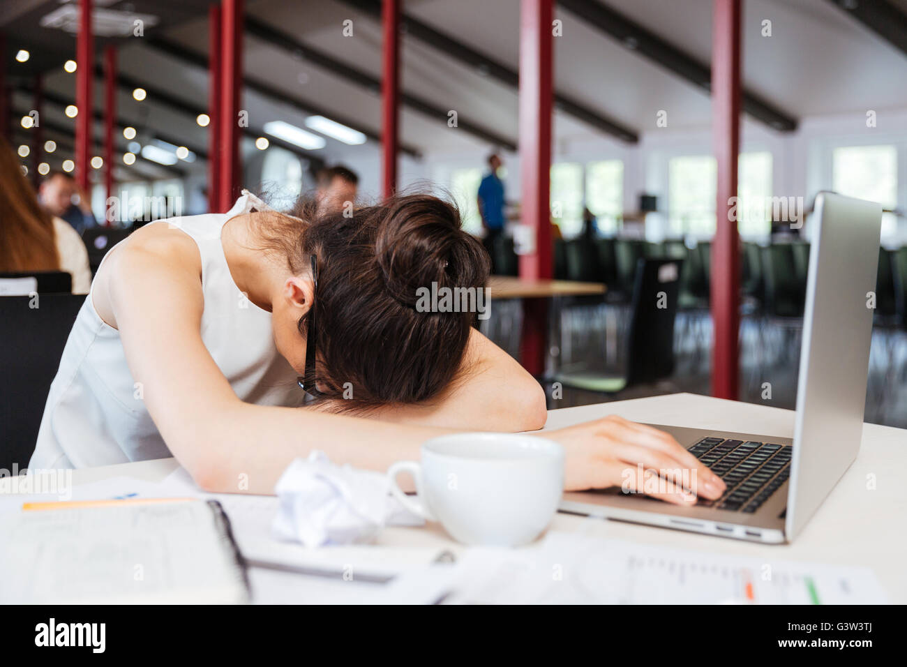 Erschöpft, müde junge Geschäftsfrau schlafen auf Tisch mit Laptop am Arbeitsplatz Stockfoto