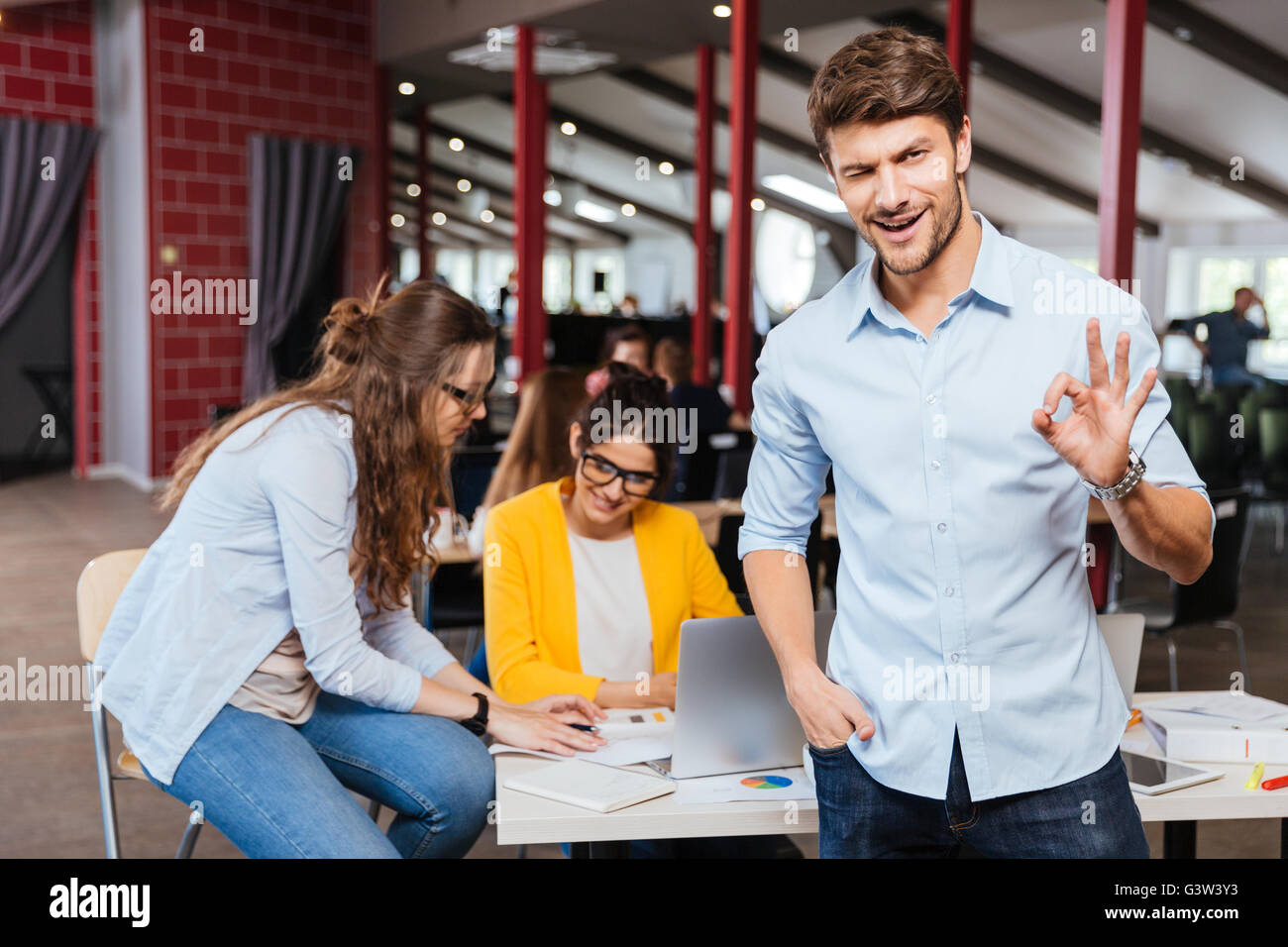 Glücklich erfolgreiche Jungunternehmer stehen und Ordnung Anzeichen mit seinen Kollegen auf Hintergrund Stockfoto