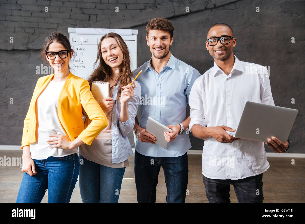 Gruppe von fröhlichen erfolgreiche junge Geschäftsleute mit Tablet und Laptop im Konferenzraum Stockfoto